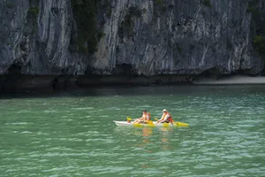在兰夏湾平静的碧绿海面上,乘坐吉婆岛精品游船的皮划艇游客在石灰岩喀斯特峭壁旁悠然划行