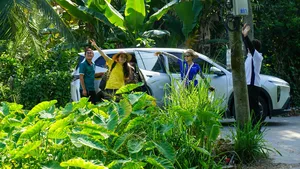 Tour riders smiling beside a parked support vehicle surrounded by lush greenery on Mekong Island near Ho Chi Minh City