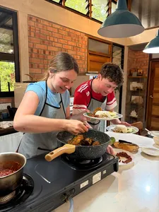 Guests tasting Malaysian comfort food in the Kebun Lidstari farmhouse kitchen in Langkawi, with a hot wok and spices on the stove