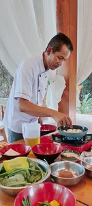 Chef Michael cooks at the counter, with pans and bowls of vegan ingredients ready for a Manggarai cooking lesson in Labuan Bajo