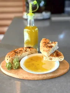 Cecahan keemasan dalam mangkuk dengan potongan roti hangat di atas dulang kayu, bersama sebotol minyak, di sebuah bengkel di Singapura — bengkel di Singapura