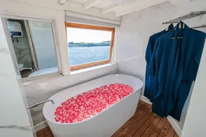 La Famille private 3D2N Komodo boat trip cabin with sea-view window and white bath fitted with red details, Labuan Bajo
