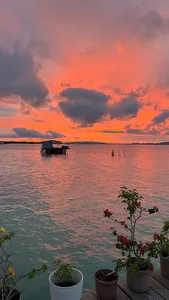 Matahari terbenam dari dek banglo air di Semporna, dengan pemandangan laut dan rumah terapung, serta penginapan Bigfin Divers di atas teluk