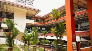 Open-air hawker centre courtyard in Singapore with palm trees, walkways and seating around an orange column — Singapore hidden gems