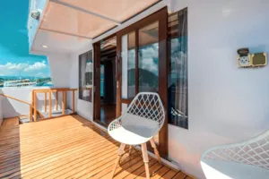 Sleek white phinisi deck balcony outside a private 3D2N Komodo cruise, with chairs overlooking Labuan Bajo