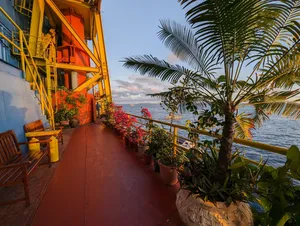 Tiled walkway beside orange rig structures, potted plants and an ocean horizon at sunset during a Seaventures Dive Rig stay