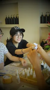 Perfume Play perfume workshop in Singapore: a host helps participants add fragrance drops at a table with small bottles and labelling cards