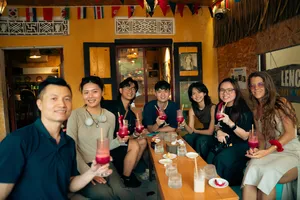 会安隐秘鸡尾酒之旅中，朋友们在色彩缤纷的街边小店里举起红色鸡尾酒，用吸管轻轻碰杯