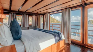 Deluxe phinisi cabin with a double bed and sea-view windows on a 4D3N shared Komodo cruise, Komodo Island