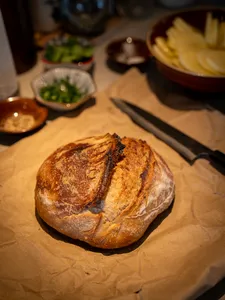 Crusty bread loaf on parchment with small side dishes on a dining table, set up for tapas sharing during private dining Singapore