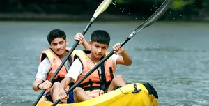 Two paddlers in yellow kayaks paddling on choppy water near the shore in Langkawi during a guided island adventure