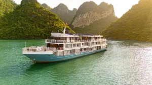 Oasis Bay party cruiser on Halong Bay in daylight, cruising past steep green karst mountains across calm emerald water