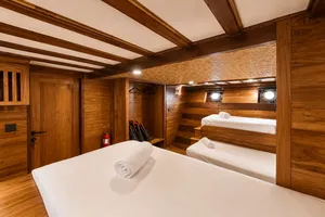 Travass Life phinisi cabin with two berths, rolled towels and warm wood-panelled walls, for a rare 3D2N shared trip on Komodo Island