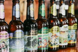 Bottles of craft beer with colourful labels lined up at a brewery counter for tasting in Shangri-La