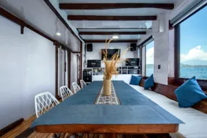 Phinisi dining table in an onboard lounge with ocean views on La Famille’s private 3D2N Komodo cruise in Labuan Bajo