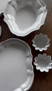 Antique-style scalloped ceramic plates and serving platters on a wooden table at Ina Atelier workshops in Singapore