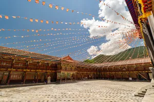 Courtyard walkway inside a Tibetan monastery in Shangri-La, lined with wooden rooms and strings of prayer flags fluttering above