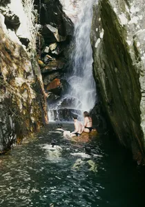 Swimmer relaxing in a narrow waterfall pool between jungle cliffs on a secret waterfall outing from Hoi An