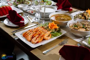 Platter of prawns and bowls of soup on a dining table, set for dinner on a Sunshine Golden Cruises luxe 2D1N Cat Ba cruise