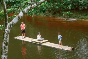 Guests enjoying bamboo rafts on a shaded river during a regenerative homestead stay on Bidayuh ancestral land near Kuching