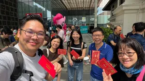 Team members smiling and holding Monopoly-style red cards during a real-life game in Katong-Joo Chiat, Singapore for team building Singapore