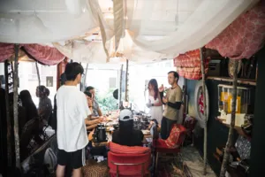 People chatting beside coffee equipment in a cosy tent café during hands-on coffee roasting and bagel brunch workshops in Singapore