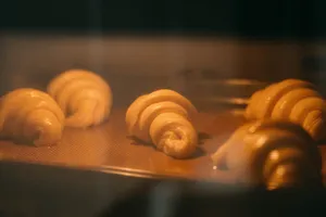 Croissants baking on a tray in a warm oven during a French Cooking Lab croissant workshop in Singapore