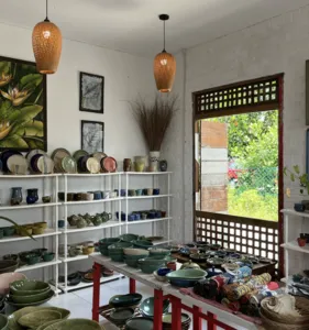White-walled ceramic room display at Ilham Ceramic Studio in Langkawi, with shelves of bowls and woven pendant lamps