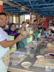 Group pottery class in a covered Langkawi studio, visitors shaping and decorating small bowls at shared worktables