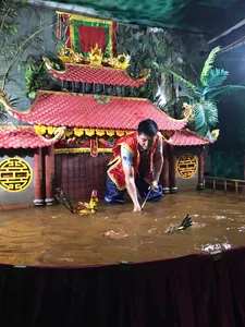 在河内一场私人演出中,来自 Bamboo Life 的戏偶师身着戏服,蹲在被水淹没的舞台水幕后方