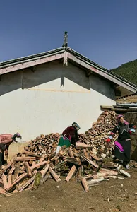 Traditionally dressed villagers carrying firewood at a countryside guesthouse in Lijiang during a Yi & Naxi village trek