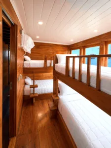 Wooden phinisi cabin with twin berths and panoramic windows for a 3D2N shared Komodo cruise, Komodo Island