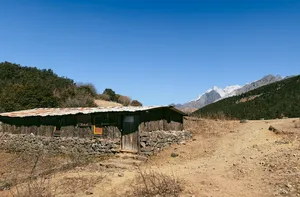 Wooden mountain camp hut overlooking distant peaks during a guided hike to Jade Dragon Snow Mountain from Lijiang