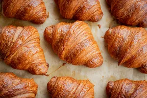 Croissant keemasan di atas kertas pembakar, baru dikeluarkan dari ketuhar, dalam pengalaman croissant dan kopi French Cooking Lab di Singapura