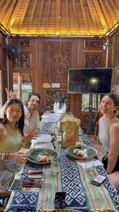 Smiling guests seated at a Bali dining table with plates and tempe snacks, sharing a workshop moment with TempeGo Experience