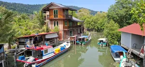 Boats moored along a Langkawi jetty beside stilted waterfront houses, part of a cycling tour through villages