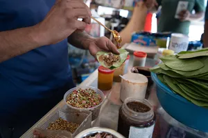 Hands preparing food at a table of spice trays and banana leaves during a Secrets of the Streets visit, Singapore hidden gems