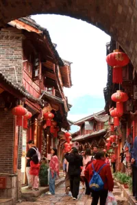 Busy narrow street in Lijiang’s old town with red lanterns and wooden facades as visitors walk through the cobbled lane