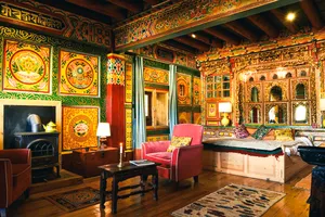 Ornately decorated Tibetan-style room inside Ferme Liotard in Shangri-La, with vivid wall hangings, cushioned chairs and lamps