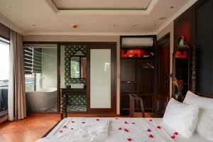 Luxury cruise suite cabin with private bath tub alcove and rose‑petal towel swans on the bed, Cat Ba 2D1N