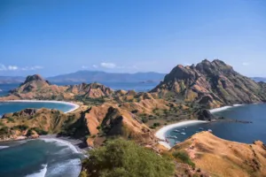 Aerial view of rugged coastline with empty sandy beaches, rocky hills and small boats in calm coves on Komodo Island