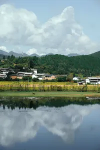 Desa tepi sungai Shaxi di Dali, Yunnan, dengan danau tenang yang memantulkan atap-atap rumah dan pegunungan berhutan selama retret eco ini