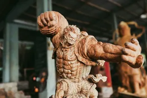 一尊雕刻木制守护像抬起手臂,陈列于会安木雕工坊内