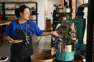 Seeker Yunnan Coffee Estate host in an apron operating a roaster machine in Lijiang’s coffee workshop