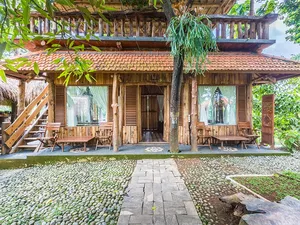 Wooden meditation pavilion with draped curtains and stone walkway at Omunity Bali retreat in Bali