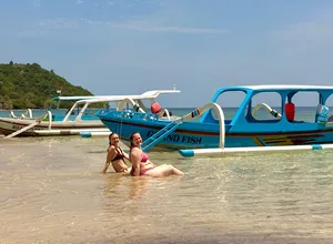 Dua penyelam snorkel meredah air di persisiran menuju bot biru putih, bersedia menerokai perairan Secret Gilis di luar pantai Lombok