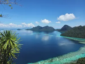 Blue bay with turquoise shallows and forested mountains near Semporna, Sabah, viewed from the Bohey Dulang hike
