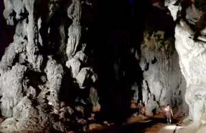 Rocky cave entrance with travellers walking along a dim chamber near Kuching on a gold-mine and jungle adventure