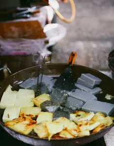 Sizzling wok of fried tofu and batter in a smoky Lijiang stall, capturing the flavours behind a local food hunt