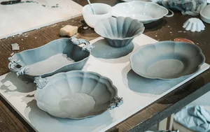 Light blue ceramic plates and shallow bowls with scalloped edges arranged on a pottery worktable at Ina Atelier workshops in Singapore